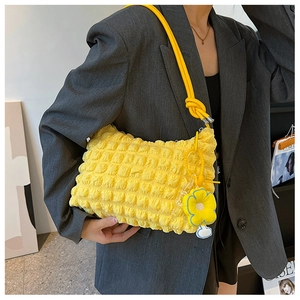 Close-up of yellow popcorn texture crossbody bag with matching flower charm and rope strap