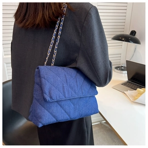 Vue arrière d'un mannequin portant le sac bandoulière en denim matelassé avec chaîne dorée