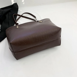 Close-up of deep brown large tote bag featuring glossy crocodile embossed texture and gold rivets