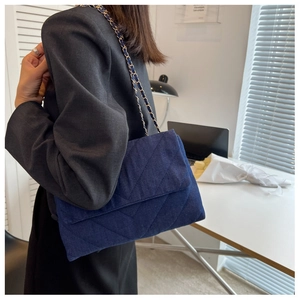 Détail du sac bandoulière en denim matelassé bleu foncé avec chaîne dorée