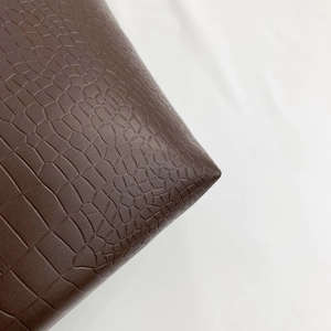 Close-up of the deep brown crocodile embossed leather texture on a shoulder bag
