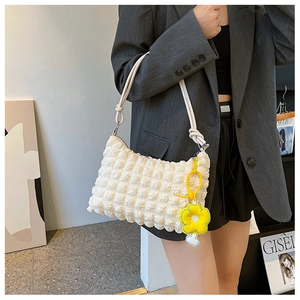 Detailed shot of beige popcorn texture shoulder bag with yellow flower charm