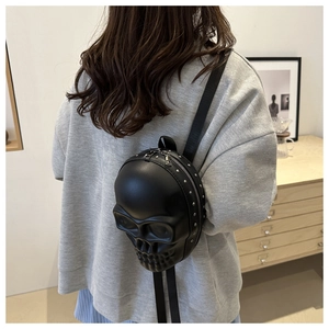 Détail d'un sac à dos crâne 3D avec rivets porté par un mannequin, style punk gothique