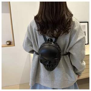 Détail d'un sac à dos tête de mort 3D avec rivets argentés sur cuir synthétique mat