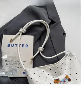 Detailed view of white polka dot bucket bag featuring 3D bear embroidery and knotted strap