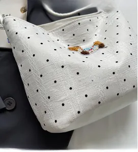 Detailed view of white polka dot bucket bag with exquisite puppy embroidery and fine texture