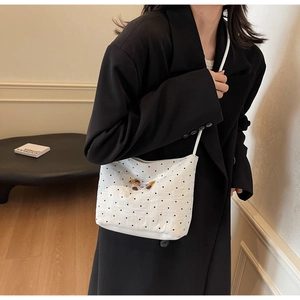 Close-up of a white polka dot shoulder bag featuring a colorful dog embroidery detail