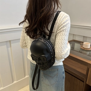 Sac à dos tête de mort noir avec rivets porté par une personne en intérieur