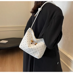 Detail of white fabric underarm bag with black polka dots and colorful bear embroidery