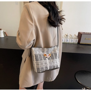 Detailed back view of a grey plaid crossbody bag with bear embroidery on a casual blazer