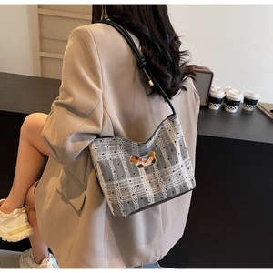 Detail of grey plaid shoulder bag with dog embroidery and black leather strap