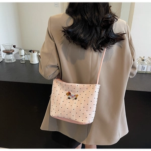 Detail view of pink shoulder bag with polka dot pattern and embroidered dog patch