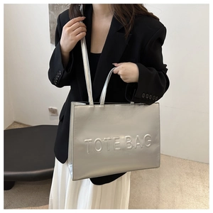 Close-up of metallic silver tote bag with embossed letters and adjustable strap