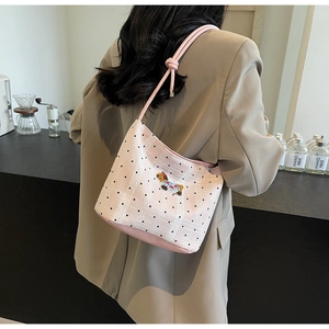 Pink canvas bucket bag with dog embroidery and polka dots on a girl's shoulder