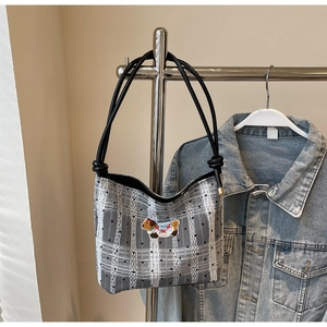 Close-up of grey plaid bucket bag with cute puppy embroidery and black cord strap