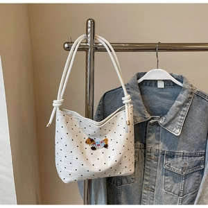 Close-up of a white polka dot bucket bag featuring a cute puppy embroidery and slim strap