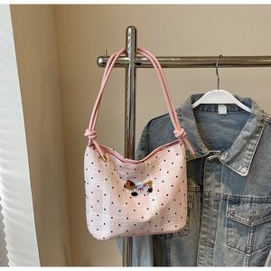 Detailed close-up of pink polka dot shoulder bag with cute puppy embroidery and knotted strap