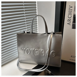 Detail of silver metallic tote bag with embossed lettering and light texture on the surface