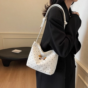 White polka dot canvas underarm bag with bear embroidery worn by a model in black