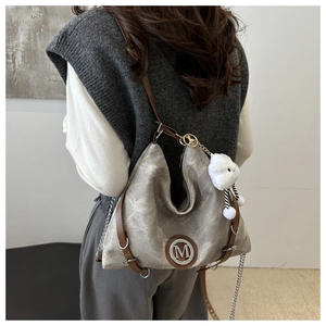 Détail du sac cabas en toile grise avec lanières en cuir marron et logo M en métal