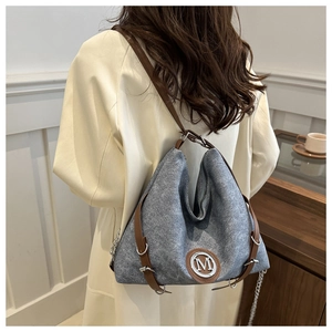 Détail du sac cabas en feutre gris avec garniture en cuir brun et logo M sur l'épaule