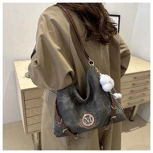 Détail du sac cabas gris en toile avec anses en cuir marron et pendentif peluche