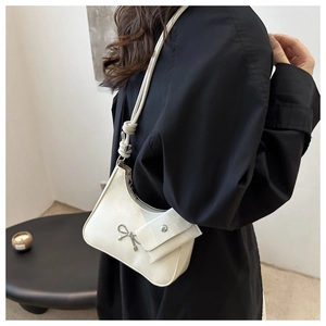 Detail of white PU crescent bag with silver bow ornament and small side pouch