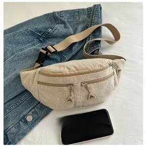 Macro detail of beige corduroy waist bag showing multi-layer zippers and phone size comparison