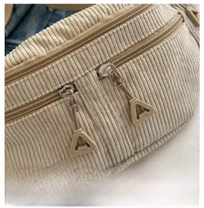 Detail of beige corduroy sling bag showing smooth zippers and textured fabric close-up
