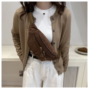 Detail of brown corduroy waist bag showing textured fabric and dual zipper pockets