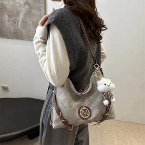 Grand sac cabas en toile grise avec anses en cuir marron et logo M, vue de côté à 45 degrés