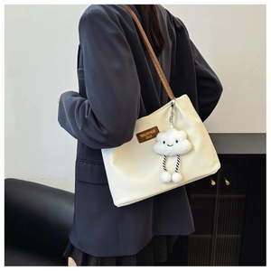 Detail of off-white corduroy tote bag with brown leather strap and cloud plush charm