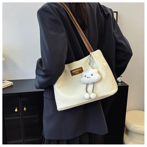 Detail of cream waffle texture tote with brown leather strap and cloud charm