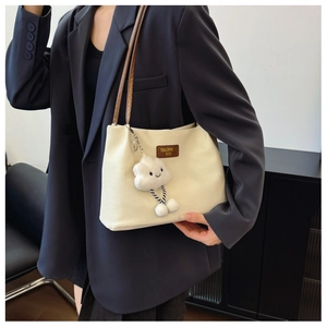 Detail of woven texture tote bag with brown leather straps and plush cloud charm