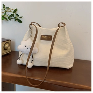 Detail of cream corduroy tote bag featuring brown leather trim and cute white cloud charm