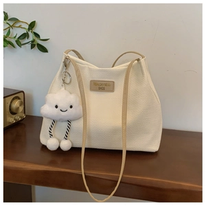 Detail of white corduroy tote bag with beige strap and cute plush cloud charm detail
