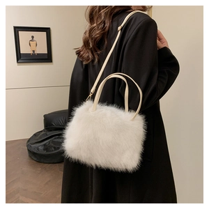 Détail d'un sac à main en fausse fourrure blanche porté sur un manteau noir élégant