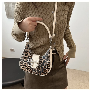 Vue détaillée du sac léopard avec boucle nœud argenté sur rabat en cuir de couleur crème