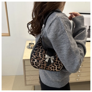 Modèle portant un sac hobo léopard avec nœud argenté dans un cadre domestique cosy