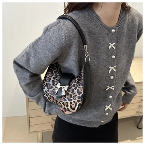 Sac hobo croissant léopard avec détail nœud en métal porté à l'épaule du mannequin