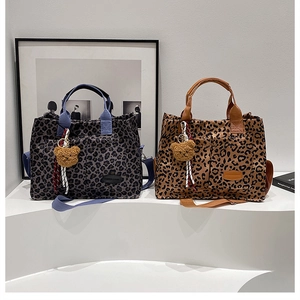 Detail view of stylish leopard print tote bags in blue and brown with plush bear charms