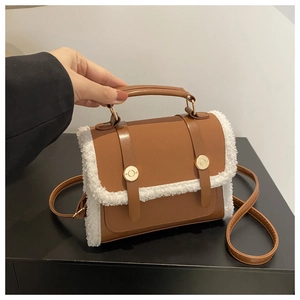 Detailed close-up of brown faux leather mini bag with white shearling trim and gold buckles
