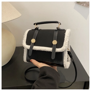 Detailed close-up of a black leather crossbody bag with white shearling trim and gold buckle