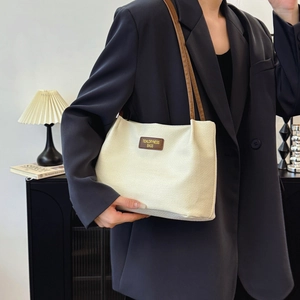 Minimalist white woven tote bag with brown leather straps shown on a model in a blazer