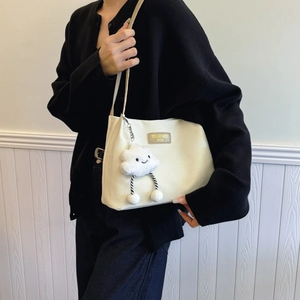 White corduroy tote bag with cloud charm shown on model in a casual home setting