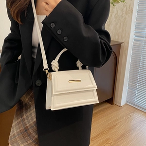 Minimalist white leather handbag with knotted handle and elegant gold metal bar detail