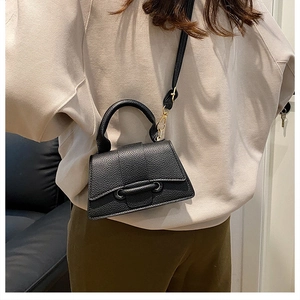 Close-up of black lychee grain leather crossbody bag shown on model in indoor setting