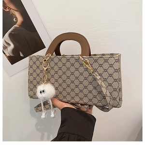 Détail du cabas rétro à monogramme avec poignées brunes et breloque en peluche