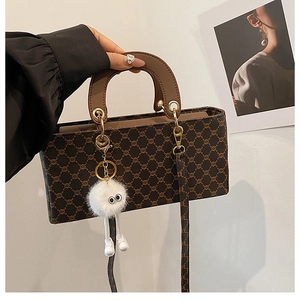 Détail du sac à main monogramme marron avec motif vintage et accessoire en peluche