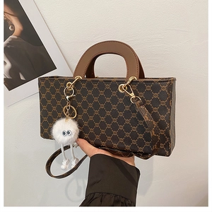 Détail du sac cabas vintage avec anses en cuir marron et un joli pendentif en peluche
